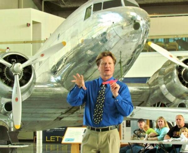 A man holding an aircraft conducting pilot training to a group of individuals.